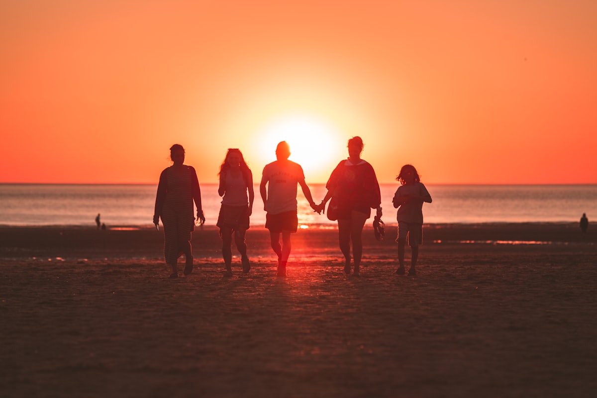 Silhouettes d'une famille marchant sur une plage au coucher du soleil