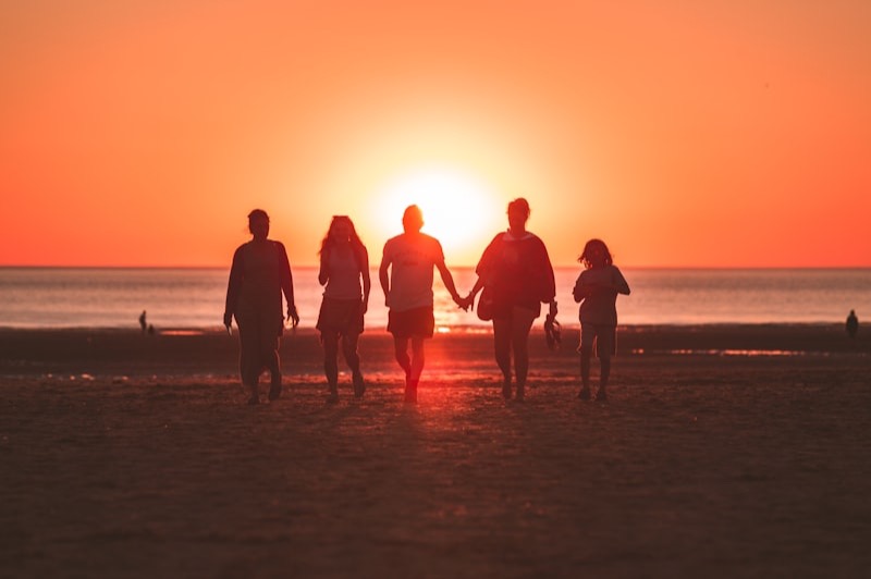 Silhouettes d'une famille marchant sur une plage au coucher du soleil