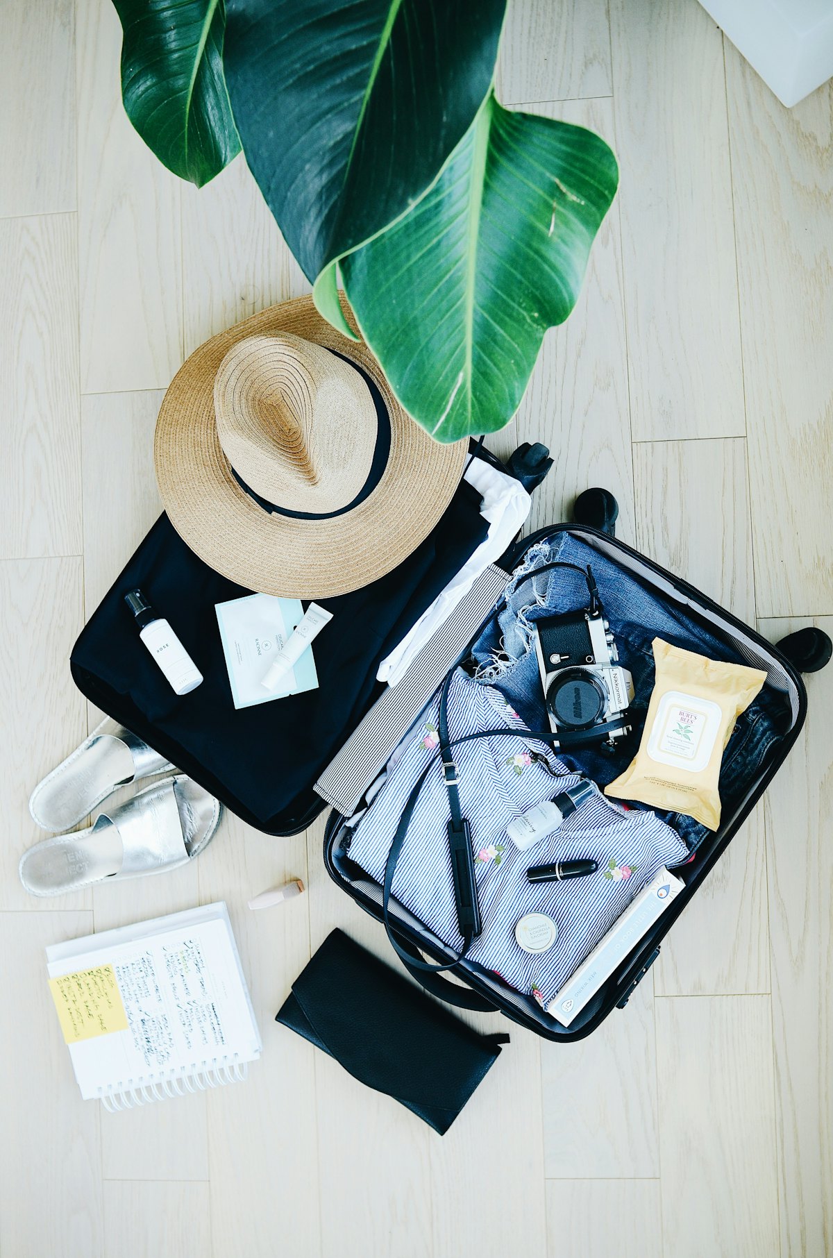 Valise ouverte avec des affaires de voyage et un chapeau