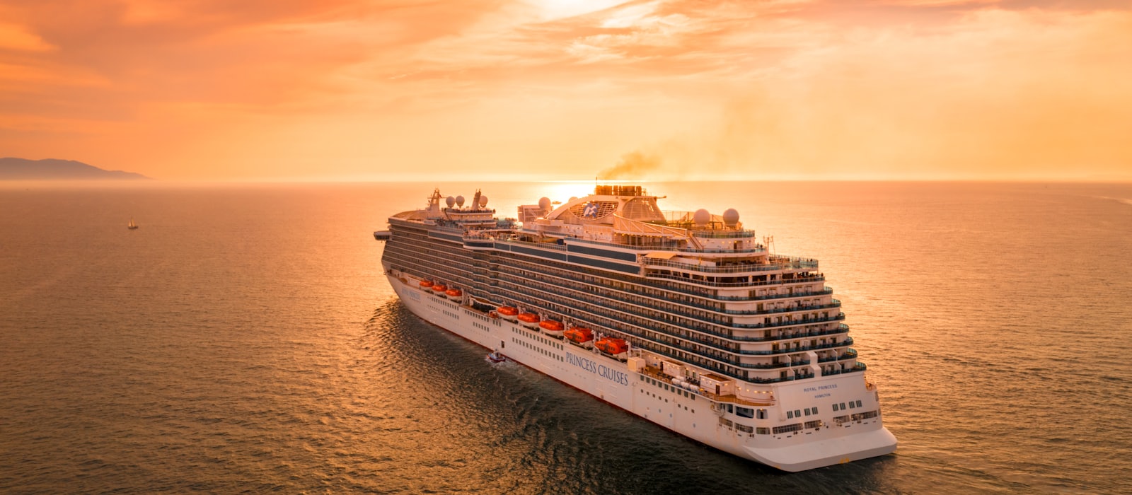 Navire de croisière blanc naviguant sur la mer au coucher du soleil