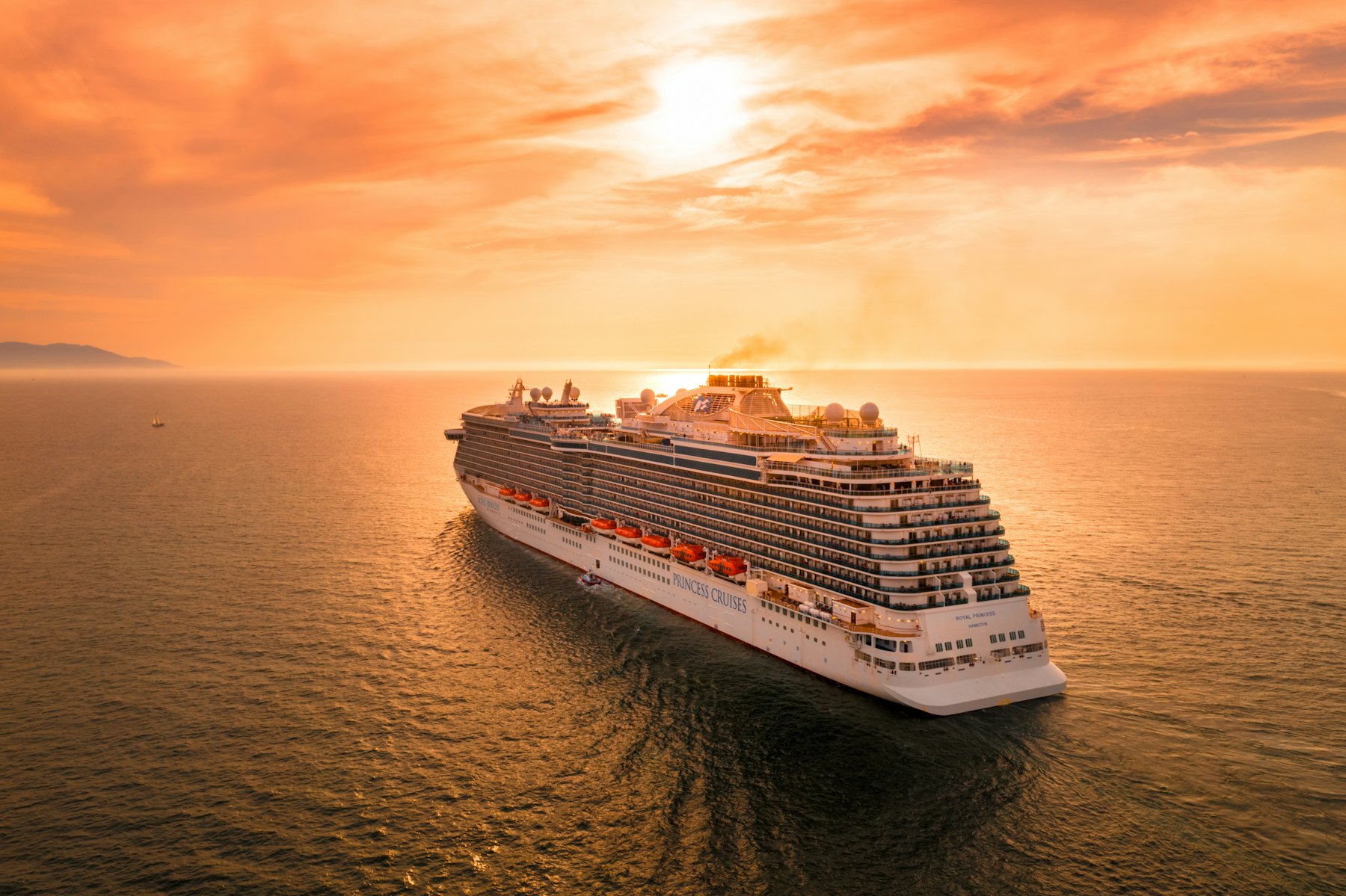 Navire de croisière blanc naviguant sur la mer au coucher du soleil