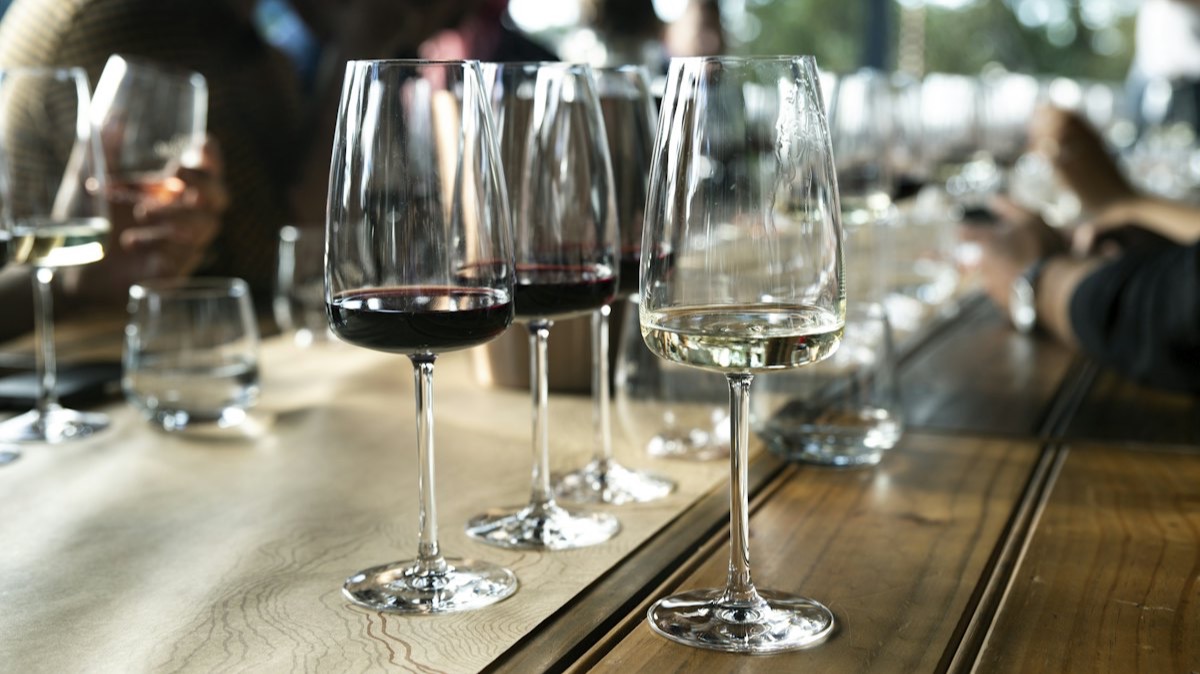 Des verres de vin rouge et de vin blanc alignés sur une table de dégustation en bois