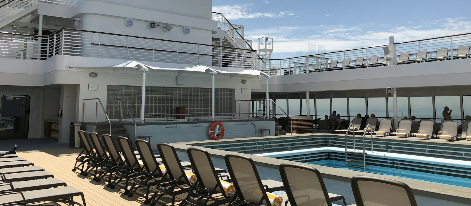 Le pont piscine d'un navire de croisière, calme, avec ses transats alignés sous un ciel bleu