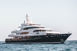 Yacht de luxe à coque sombre naviguant sur une mer calme