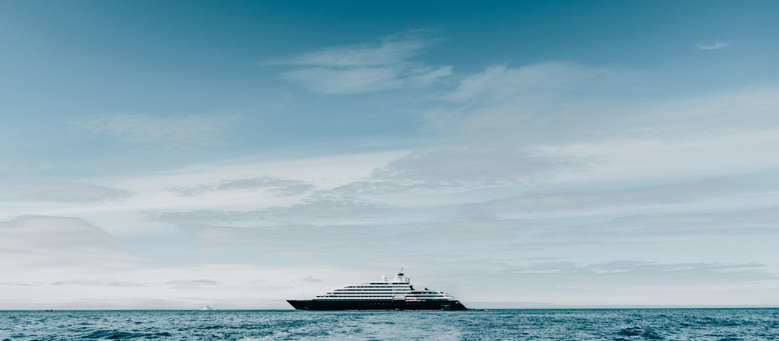 Un petit navire de croisière de luxe au mouillage au large, sous un ciel voilé