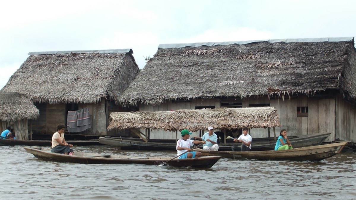 Des maisons de bois sur pilotis et des pirogues sur un bras de fleuve, en Amazonie péruvienne