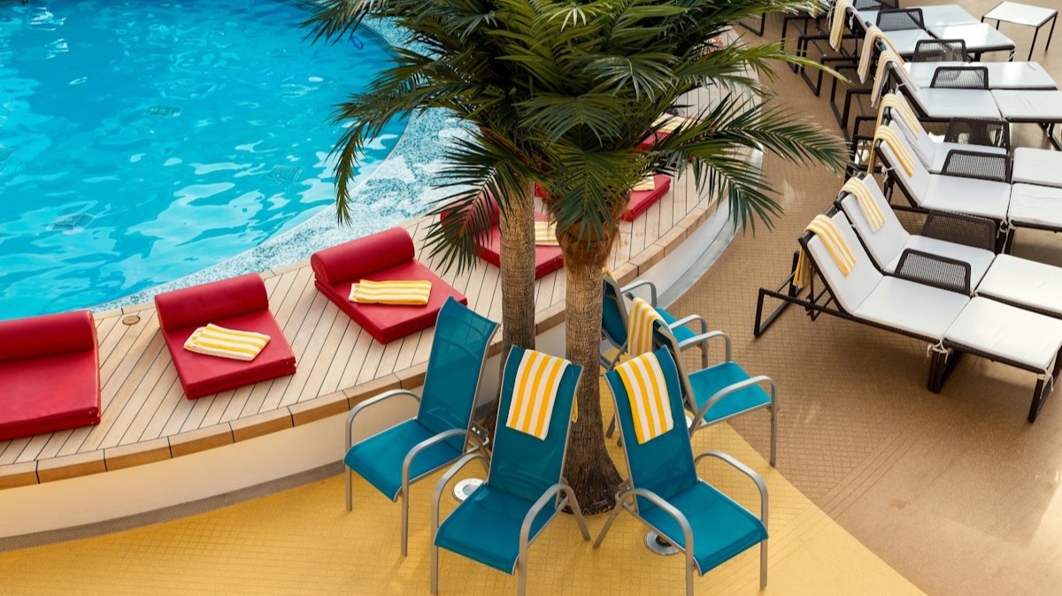 Des chaises longues bleues et blanches autour d'un bassin