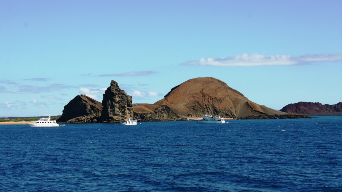 Trois petits navires de croisière au mouillage devant le rocher Pinnacle de l'île Bartolomé