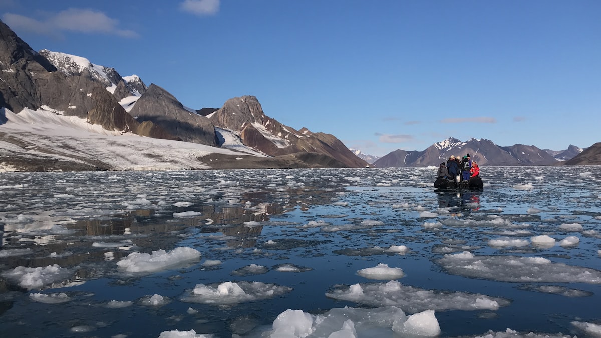 Zodiac d'expédition progressant dans la banquise devant des montagnes arctiques
