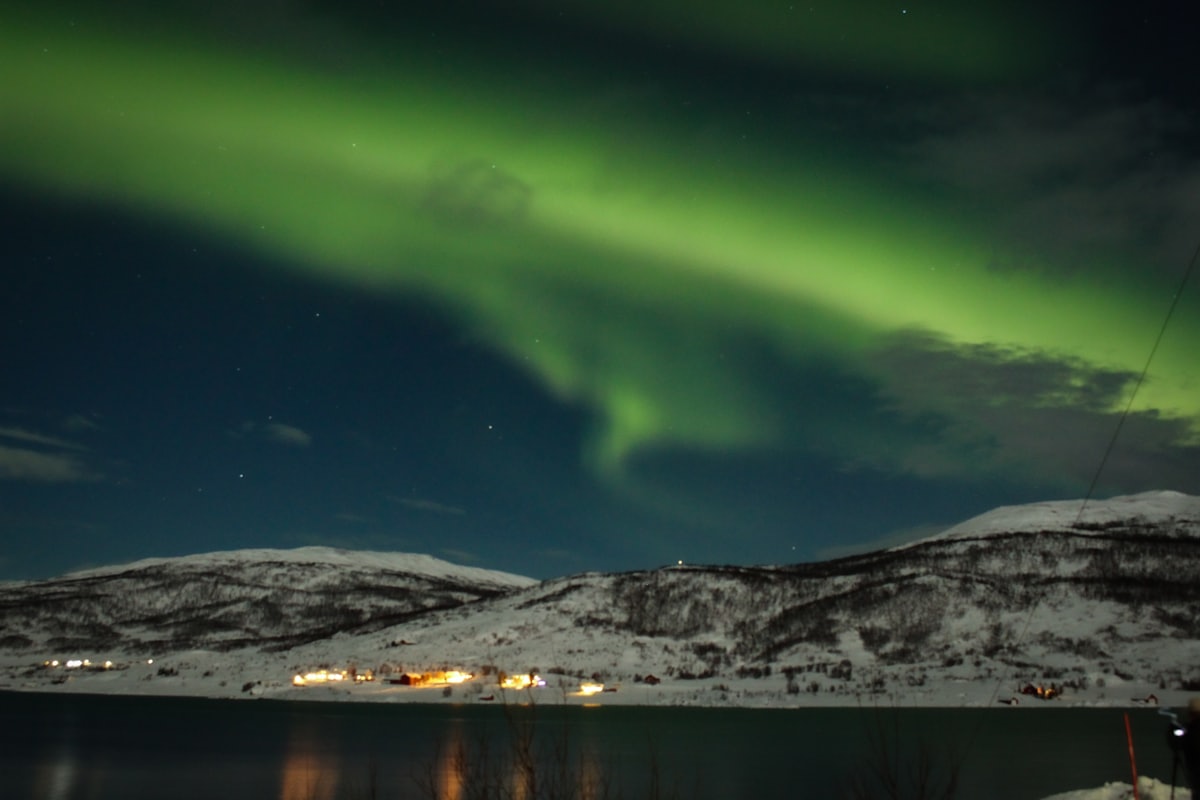 Aurore boréale verte au-dessus d'un relief enneigé du nord de la Norvège