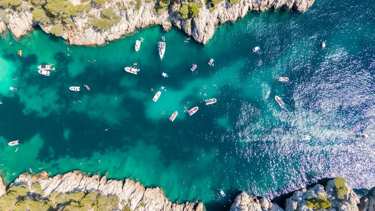 Des bateaux dans une calanque aux eaux turquoise, vue du ciel