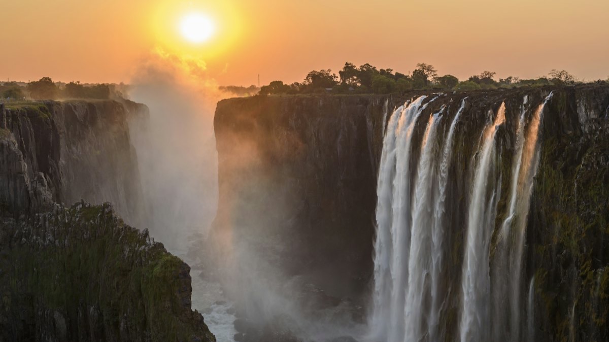 Les chutes Victoria au coucher du soleil, avec la brume qui s'élève de la gorge