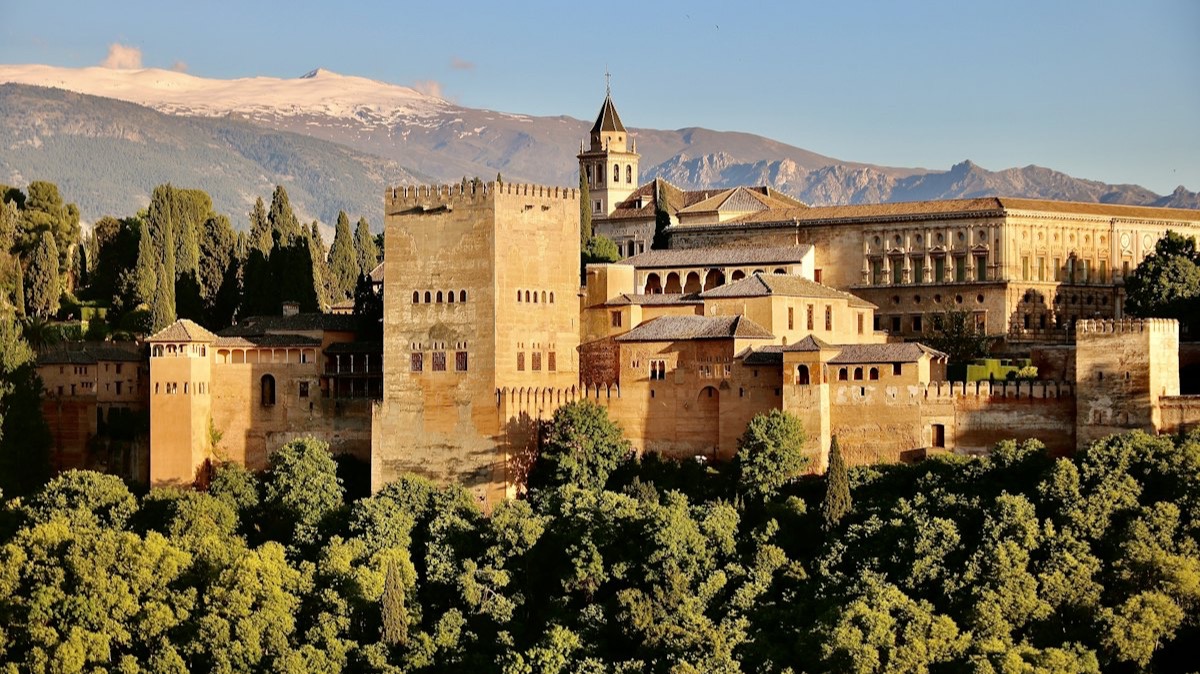 L'Alhambra de Grenade sur sa colline boisée, devant les montagnes