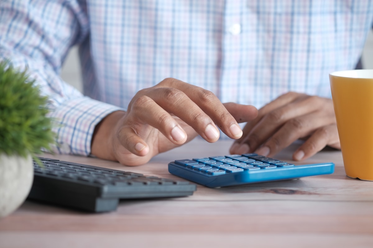 Personne utilisant une calculatrice sur un bureau