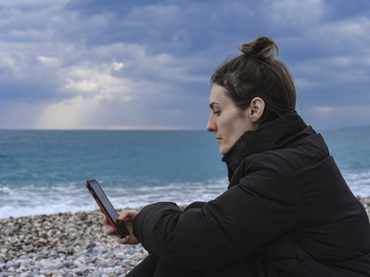 Personne consultant son téléphone face à la mer