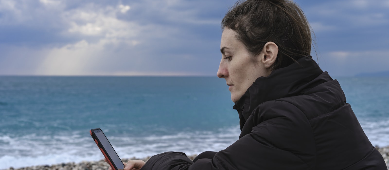 Personne consultant son téléphone face à la mer