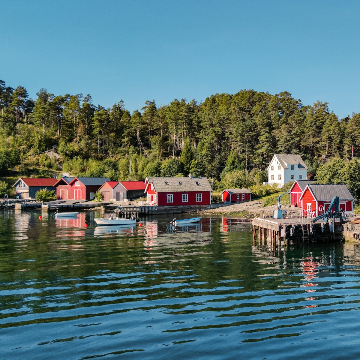 Hangars à bateaux rouges et barques amarrées dans un village du Hardangerfjord