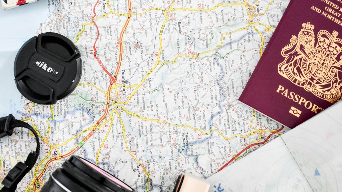 Un passeport, un appareil photo et une enveloppe posés sur une carte routière