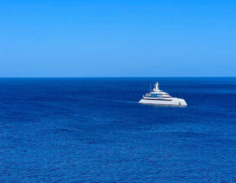 Yacht blanc naviguant seul sur une mer bleue profonde, horizon dégagé