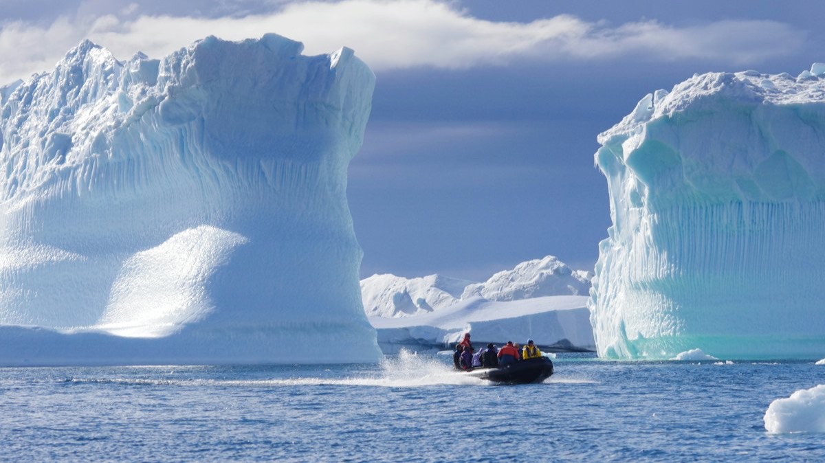 Un zodiac chargé de passagers entre deux grands icebergs