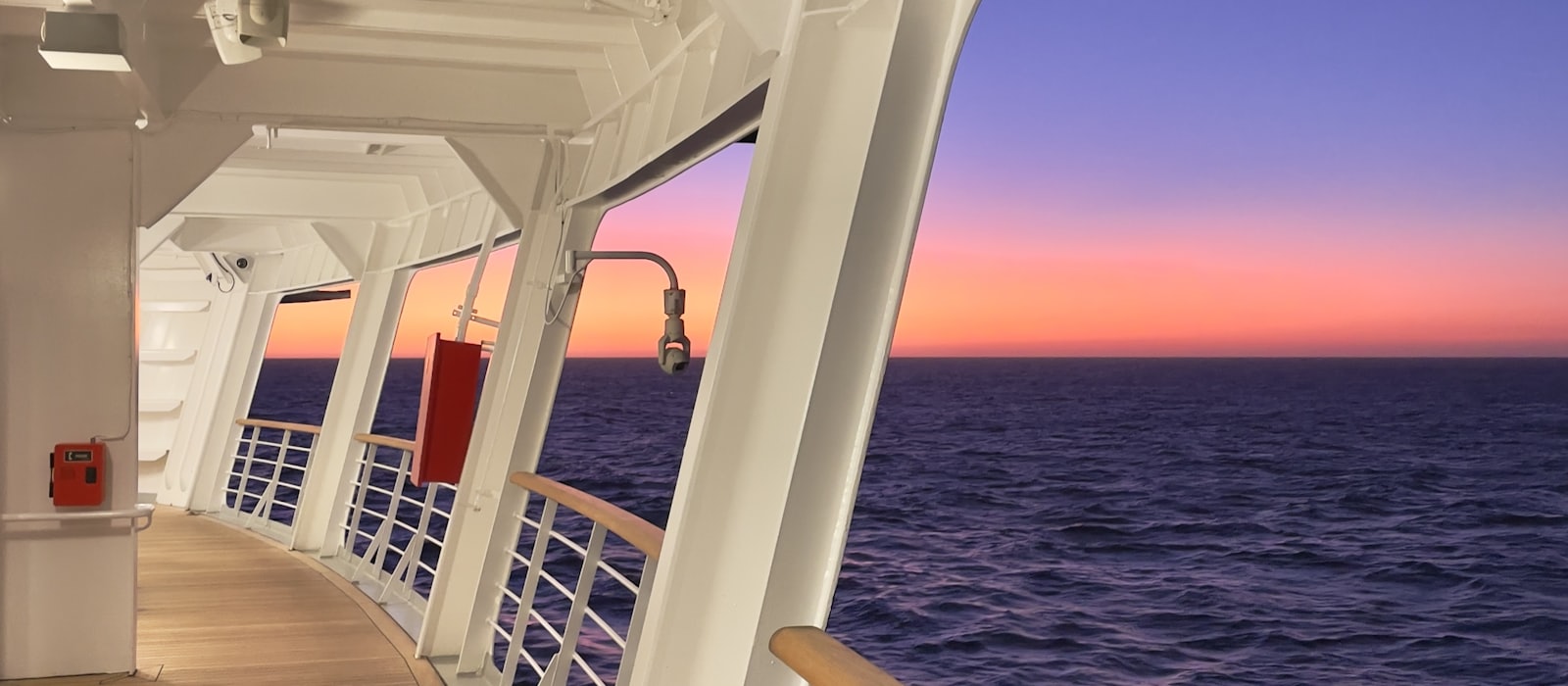 Coursive extérieure d'un navire de croisière au crépuscule, face à l'océan