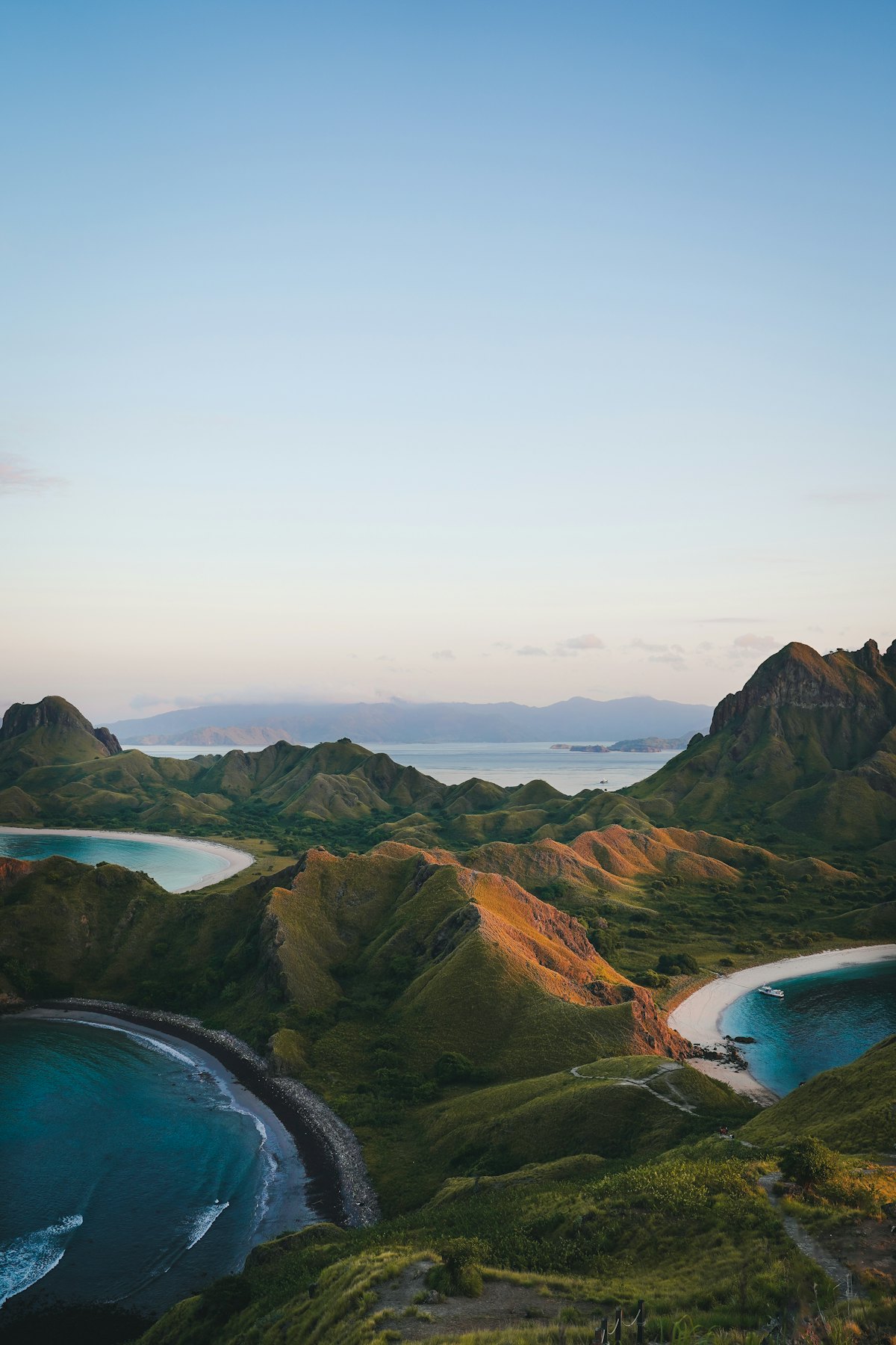 Île montagneuse aux crêtes découpées bordée de baies isolées, au crépuscule