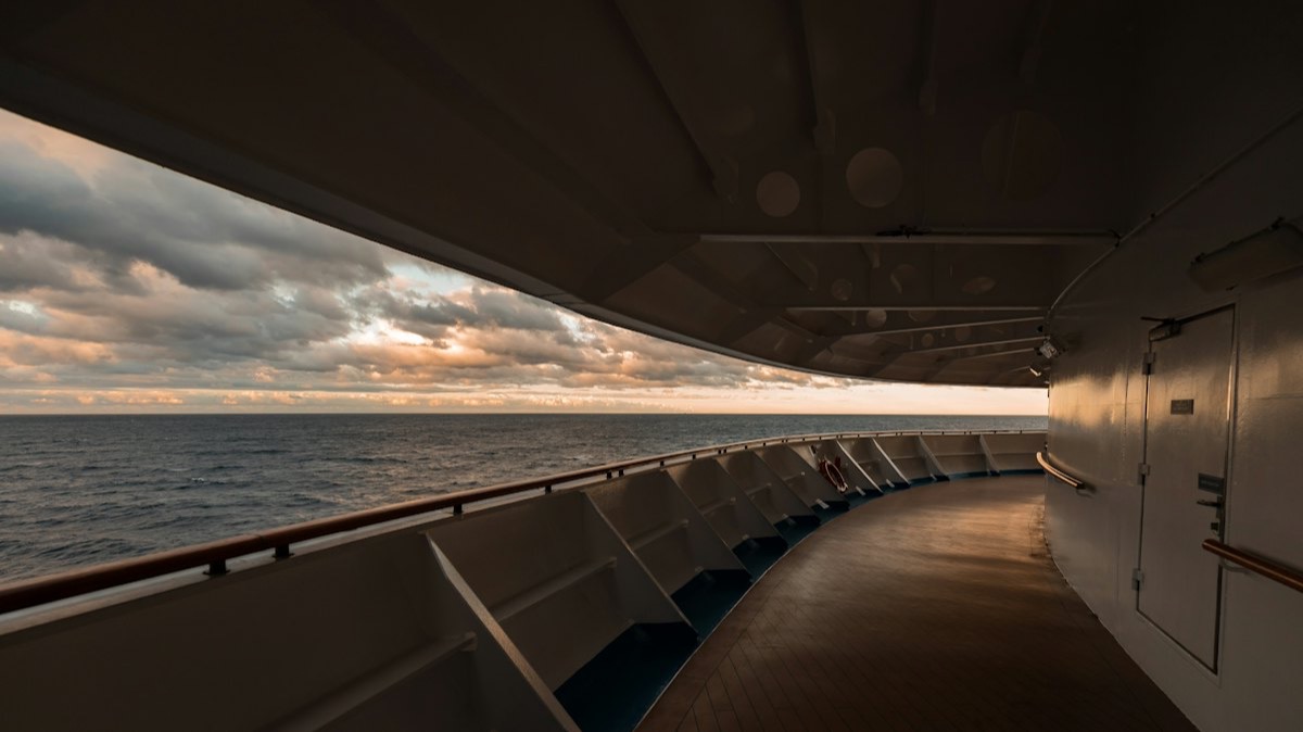 Le pont promenade couvert d'un navire de croisière, face à la mer au coucher du soleil