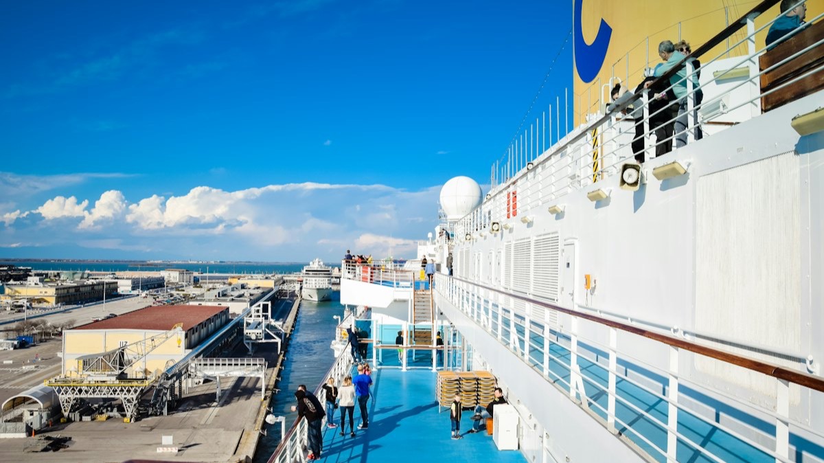 Des passagers sur le pont d'un navire de croisière amarré dans un port, par beau temps