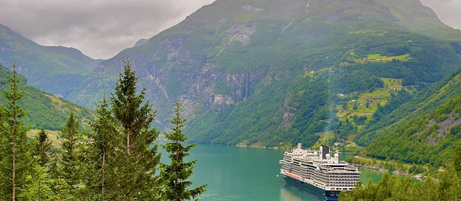 Navire de croisière à quai au fond d'un fjord norvégien bordé de montagnes boisées