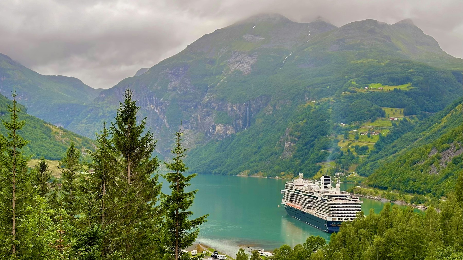Navire de croisière à quai au fond d'un fjord norvégien bordé de montagnes boisées