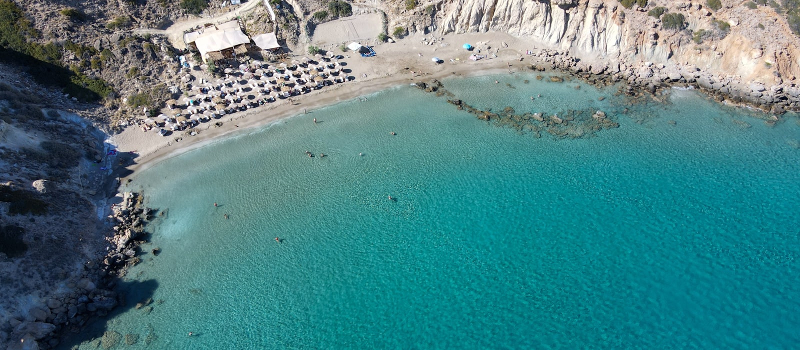 Crique grecque aux eaux turquoise vue du ciel, plage et falaises calcaires