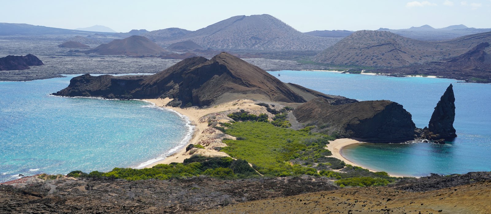 Le rocher Pinnacle et les deux plages de l'île Bartolomé vus du sommet de l'île, avec les volcans de l'archipel à l'arrière-plan
