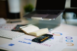 Bureau de préparation de budget : calculatrice, carnet ouvert, ordinateur portable et graphiques imprimés