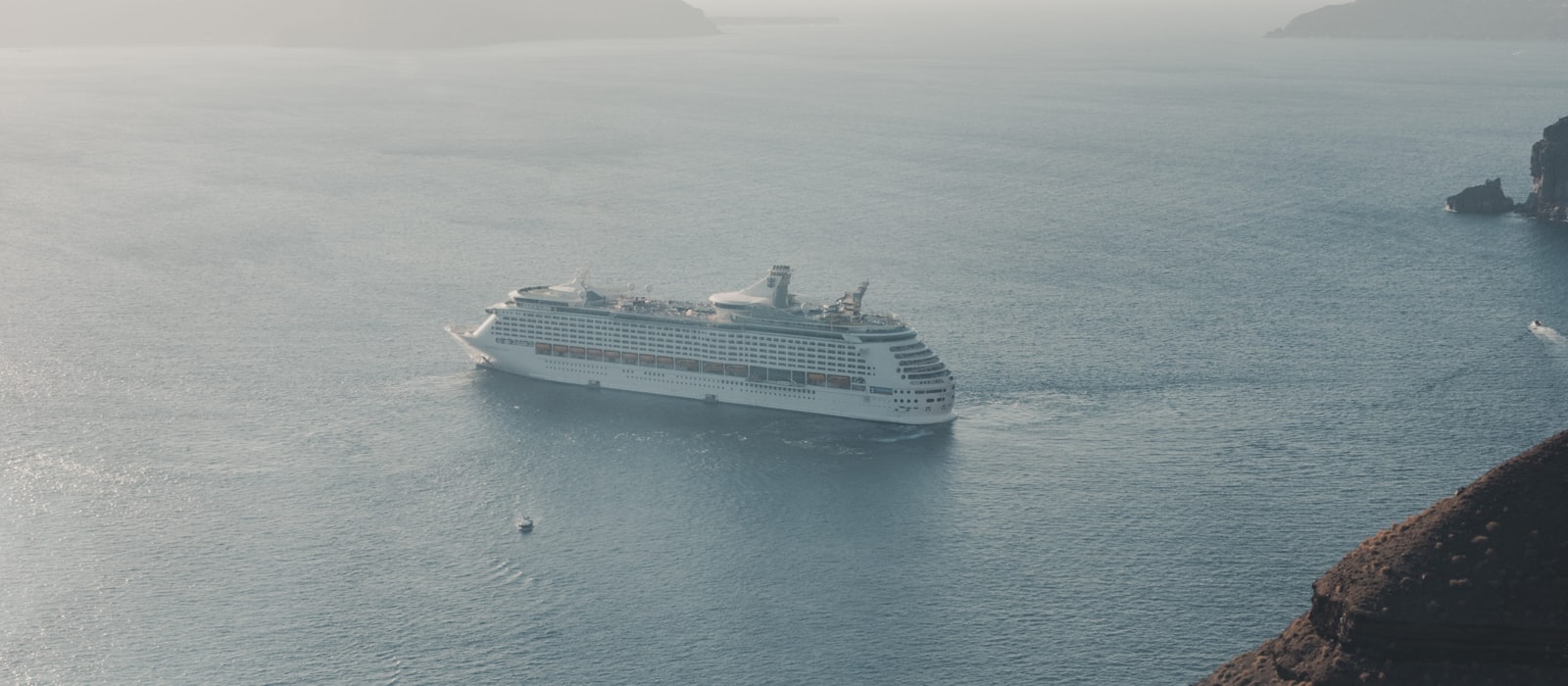 Navire de croisière naviguant dans la caldeira de Santorin, falaises et village perchés en arrière-plan
