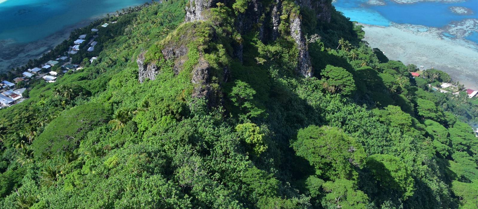 Pic volcanique dominant un lagon turquoise cerné par sa barrière de corail