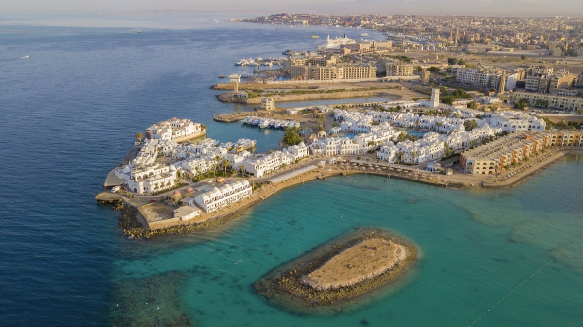 Vue aérienne d'une station balnéaire de la côte égyptienne de la mer Rouge, avec sa marina, ses bâtiments blancs et un îlot de récif