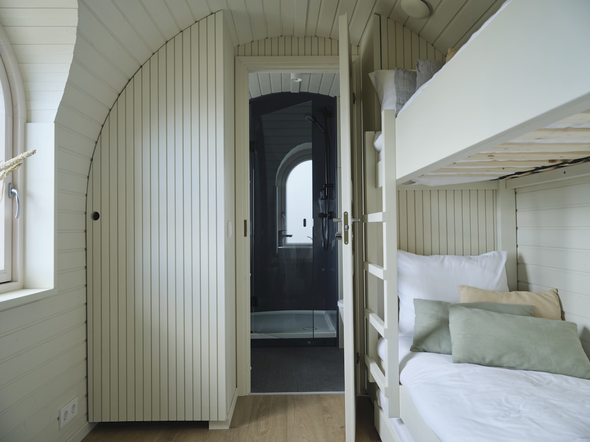 Cabine de navire compacte avec couchette, hublot et accès à la salle d'eau