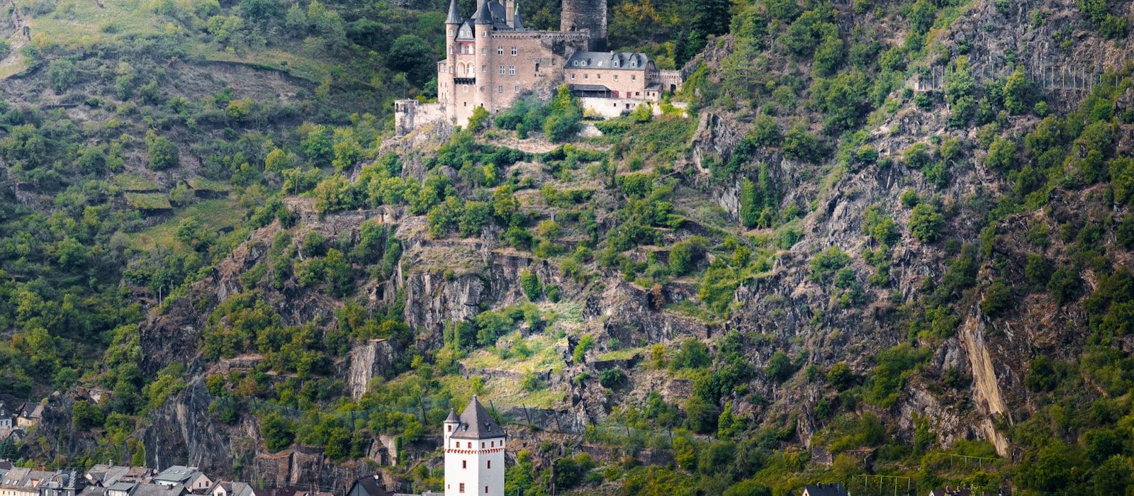 Château perché au-dessus de la vallée du Rhin, vignobles en terrasses et village au bord de l'eau
