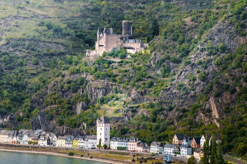 Château perché au-dessus de la vallée du Rhin, vignobles en terrasses et village au bord de l'eau