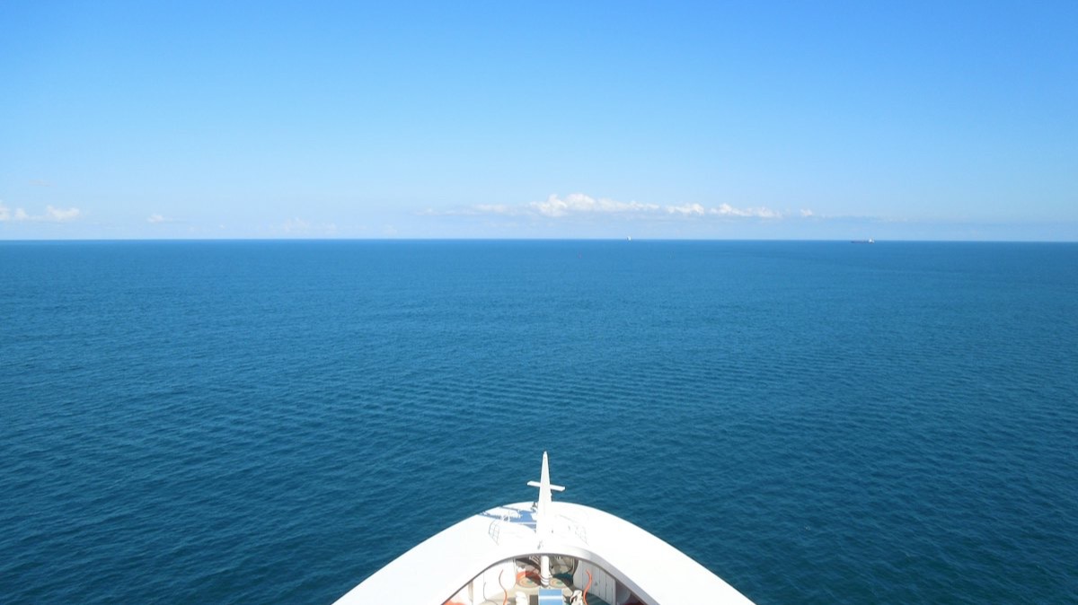 L'étrave blanche d'un navire de croisière face à l'horizon, sur une mer calme