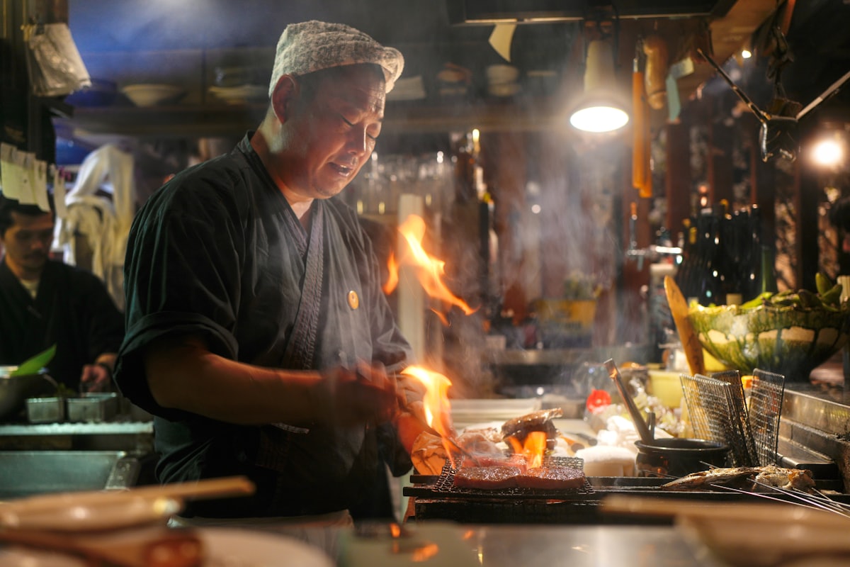 Chef cuisinant sur une plancha avec des flammes