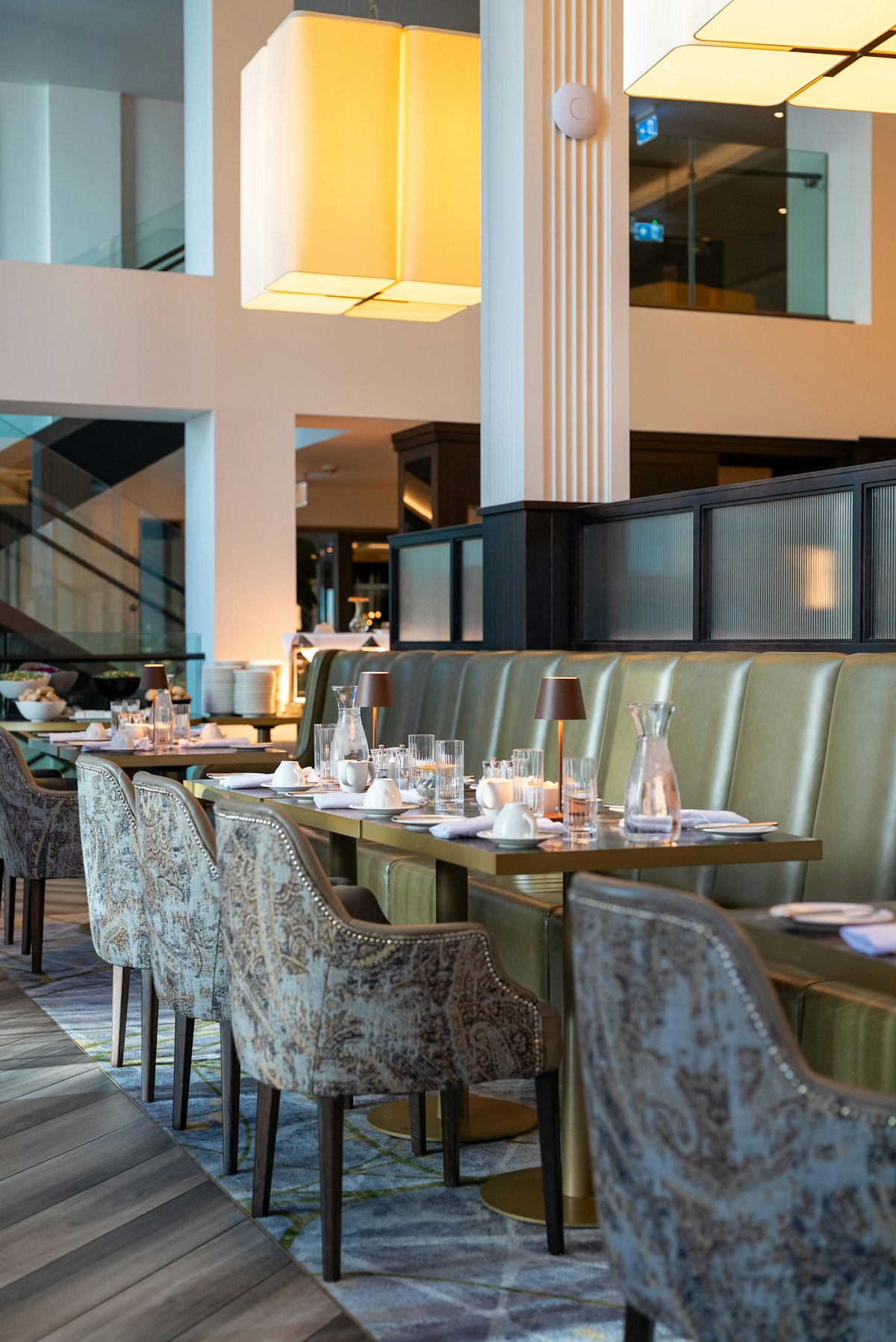 Salle de restaurant élégante avec banquettes de cuir, lampes de table et couverts dressés