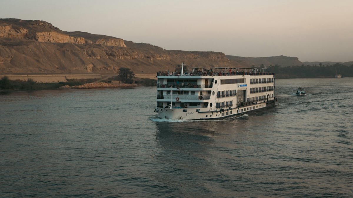 Un bateau de croisière fluviale sur un large fleuve, au pied de falaises