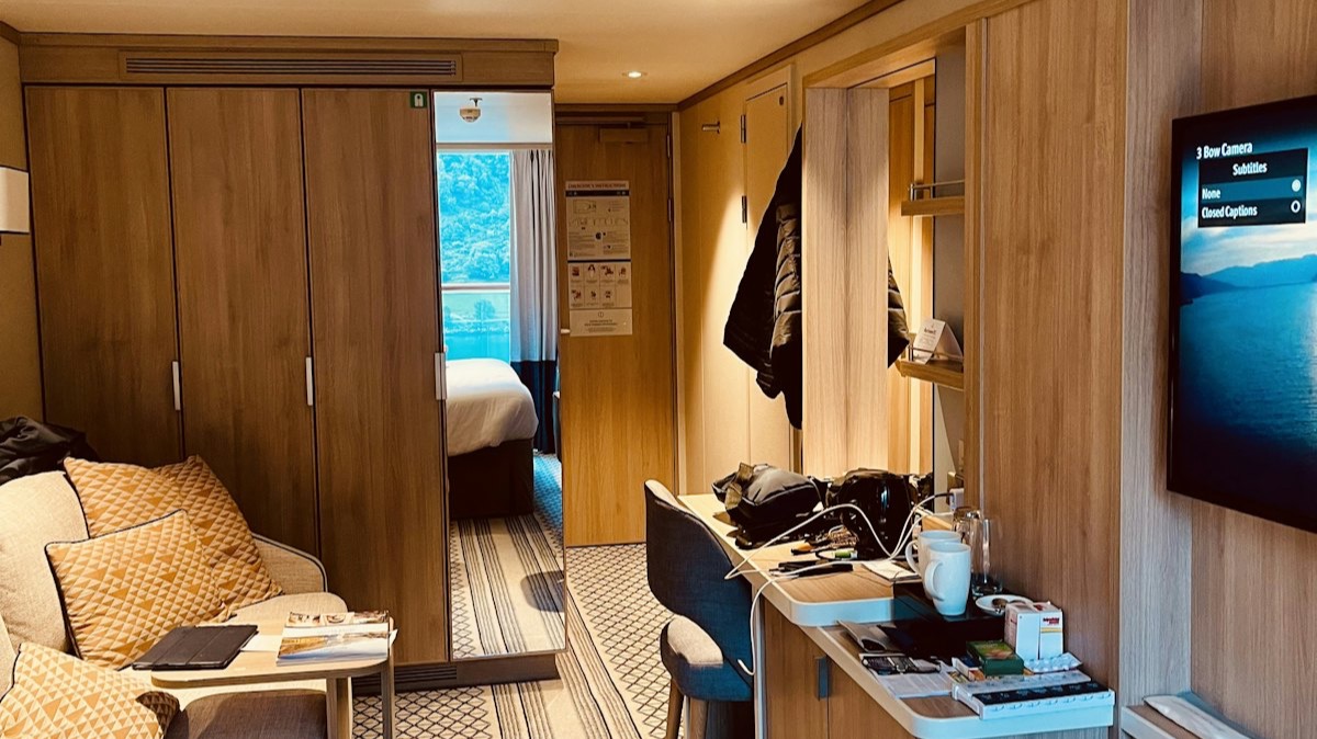 Une cabine de navire de croisière avec un canapé, un bureau et une télévision