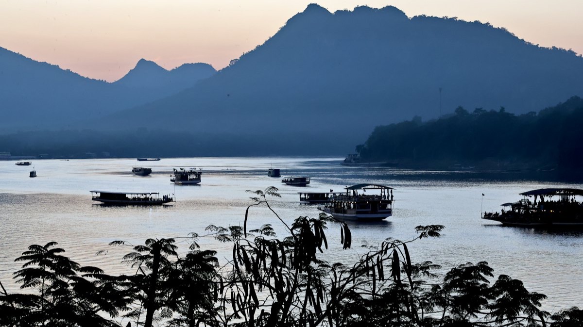 Des bateaux sur le Mékong devant les montagnes, à Luang Prabang, au Laos